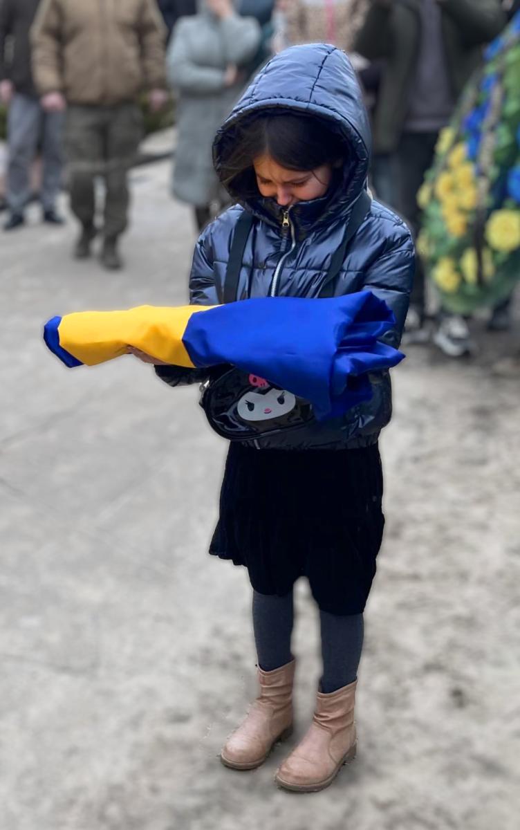 A young girl at the funeral of her father who was killed in the war.